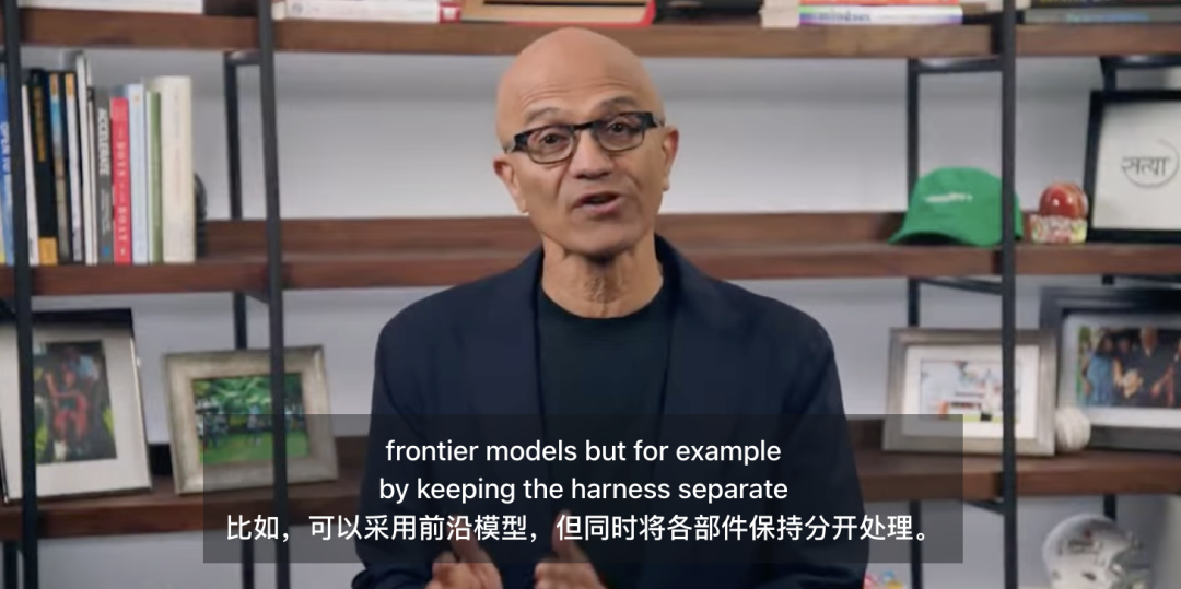 Imagem mostra o CEO da Microsoft, Nadella, em uma entrevista à CNN. Ele está vestindo um terno escuro, em frente a uma estante com livros, chapéus, porta-retratos, etc. Na parte inferior da tela, há legendas em chinês e inglês, com o conteúdo "frontier models but for example by keeping the harness separate 比如,可以采用前沿模型,但同时将各部件保持分开处理." Isso está intimamente relacionado ao contexto, que menciona Nadella propondo, na entrevista, a separação do modelo e das camadas de propriedade da empresa, mantendo os componentes separados para formar diferentes arquiteturas, permitindo que a empresa retenha o controle sobre dados etc., enfatizando o controle da empresa sobre o sistema de IA.