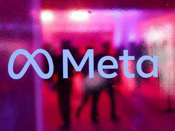 图片展示了Meta的标志,标志由无限符号“∞”和“Meta”字样组成,背景为模糊的红色和紫色灯光效果,隐约可见多人影。该图片位于介绍Meta计划在2026年9月开始生产新定制人工智能芯片的文档中,与上下文关系紧密,直观呈现了Meta品牌标识,为报道内容增添了视觉元素,强化了品牌认知。