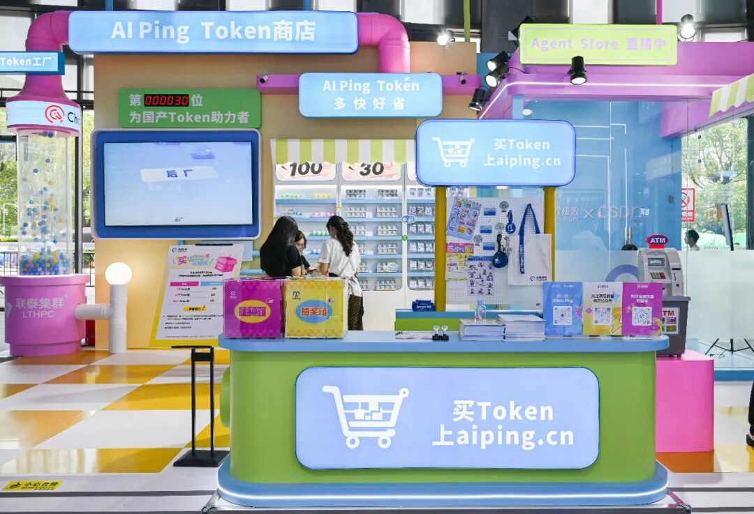 图片展示的是清程极智在WAIC 2026展会的AI Ping Token商店区域。商店以绿色、粉色为主色调，设有“AI Ping Token商店”“AI Ping Token多快好省”“Agent Store”等标识牌。柜台上摆放着多种商品，如笔记本、U盘等，柜台下方有“买Token上aiping.cn”的标识。背景中还有“Token工厂”“LTHPC”等标识，以及“第000030位为国产Token助力者”的提示牌。该图片直观呈现了清程极智在展会中展示的AI Ping Token相关产品及宣传内容。