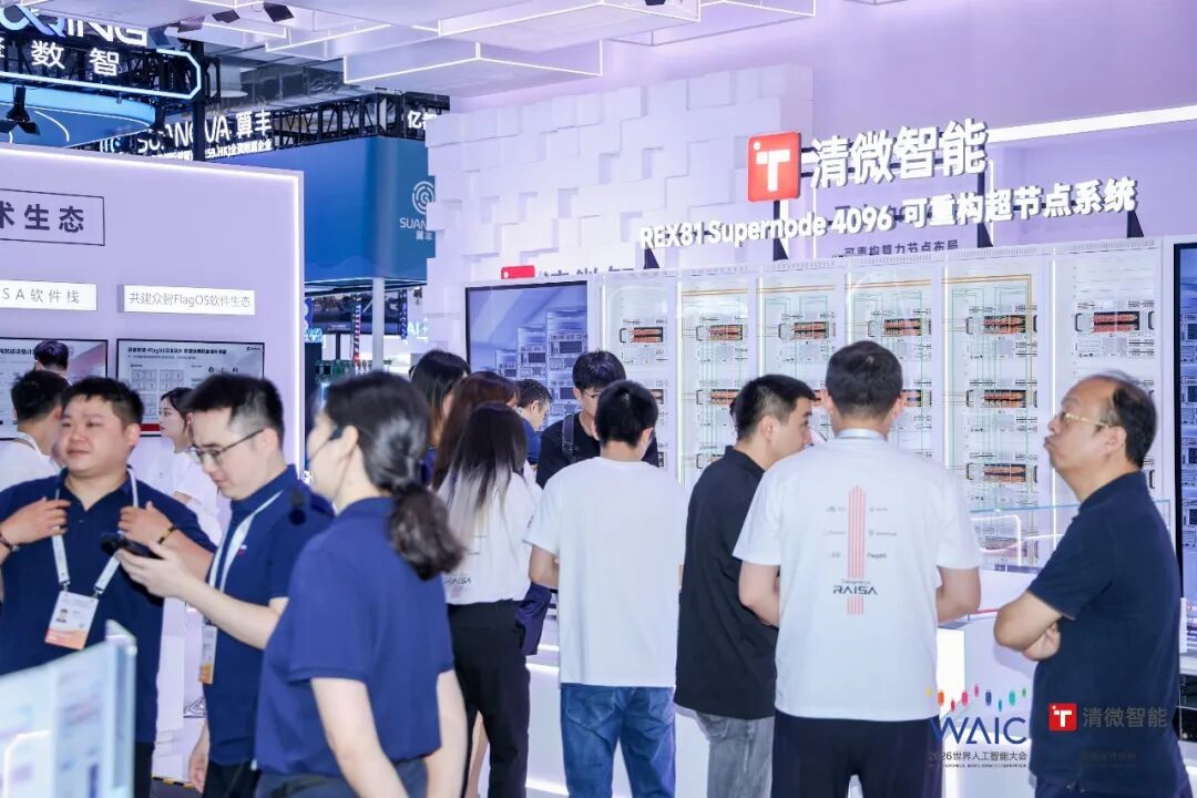 图片展示了清微智能在WAIC 2026展会上的展位。展位上方有"清微智能"及"REXT31 Supernode 4096 可重构超节点系统"字样,背景为白色方块装饰墙。展位内摆放着多台设备,旁边有工作人员介绍。参观者众多,有的在认真听讲,有的在仔细观看设备。该图片与上下文紧密相关,直观呈现了清微智能在展会中展示的可重构超节点系统及相关产品,体现了其在AI芯片领域的参展情况。